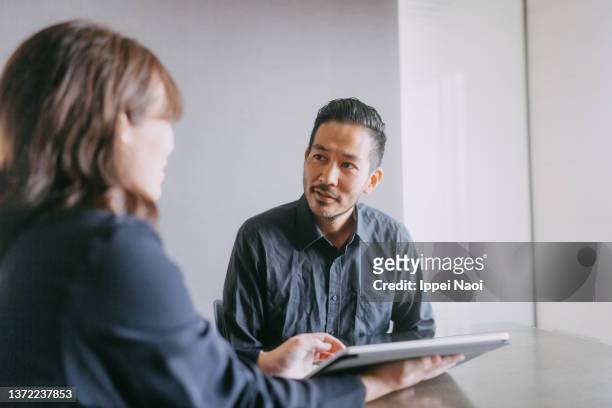 man meeting female banker for financial advice - office japan stock-fotos und bilder