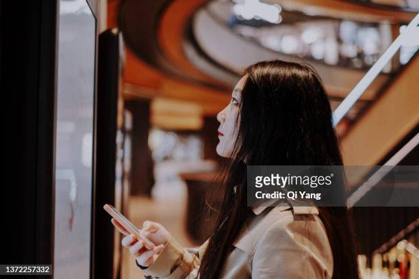 young asian businesswoman using the touch screen in shopping mall - shopping centre screen stock pictures, royalty-free photos & images
