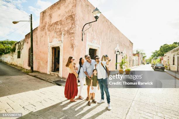 wide shot of smiling multigenerational family taking selfie in street while exploring town during vacation - 3 men standing outdoors stock pictures, royalty-free photos & images