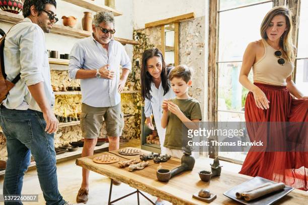 Wide shot of grandmother and grandson looking at handcrafted items in boutique while shopping with family  during vacation