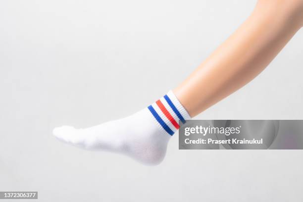woman feets in warmwhite socks with blue and red stripes - white women feet fotografías e imágenes de stock