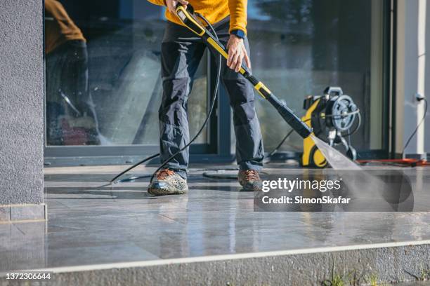 mann putzt die terrasse mit hochdruckreiniger - high pressure cleaning stock-fotos und bilder