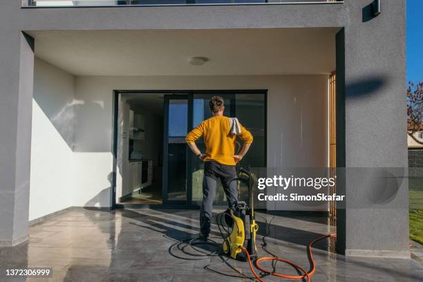 mann macht eine pause von der reinigung der terrasse der wohnung - high pressure cleaning stock-fotos und bilder