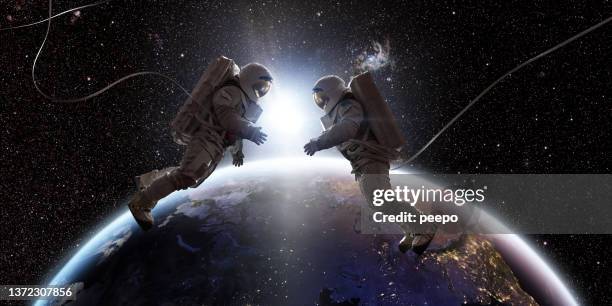 two astronauts in space facing each other in front of earth - outer space stockfoto's en -beelden