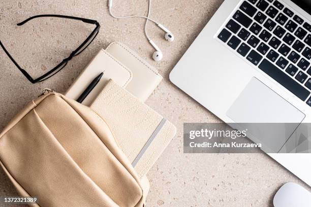 beige woman handbag with purse, note pad, pen, eyeglasses and in-ear headphones, lap top and computer mouse on concrete background from above, top view - computer mouse table stock pictures, royalty-free photos & images