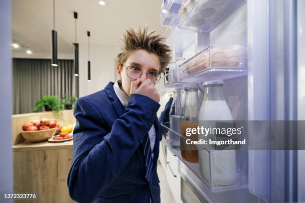 teenage boy smells taking a food out of the fridge. - funny fridge stock pictures, royalty-free photos & images