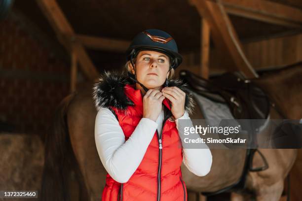 female jockey wearing helmet with horse in the background - equestrian event stock pictures, royalty-free photos & images