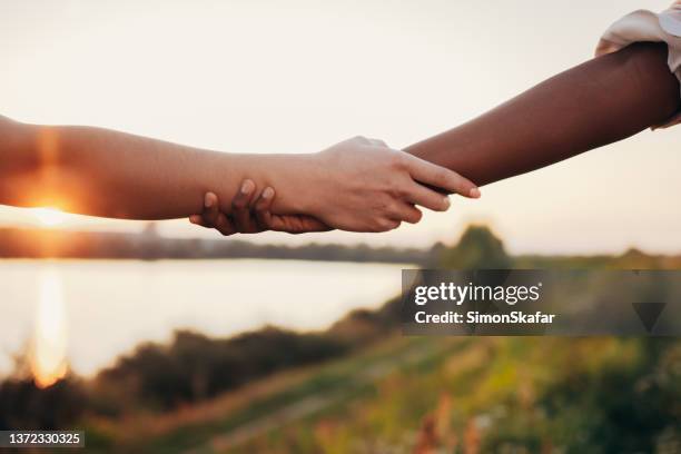 primo piano di due donne bianche e nere che si tengono per mano - side by side foto e immagini stock