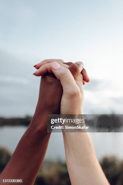 gros plan de femmes se tenant la main avec une couleur de peau différente - mains jointes photos et images de collection