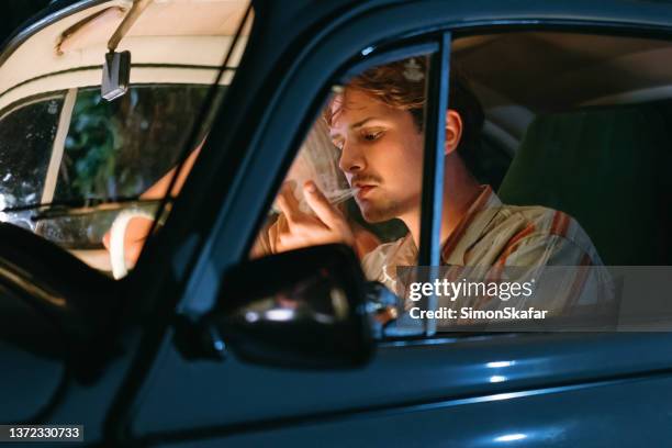 young woman sitting beside man smoking marijuana joint in car - cannabis concentrate stock pictures, royalty-free photos & images