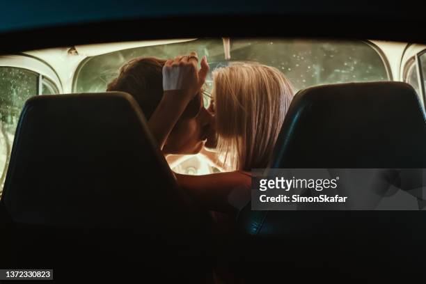 young couple kissing each other in car during date - peck stockfoto's en -beelden