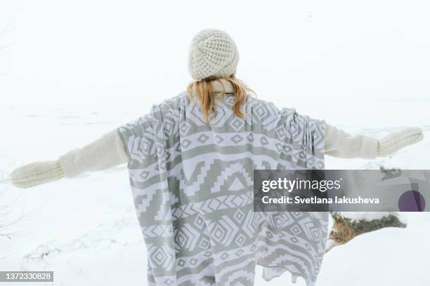 a woman in white winter clothes stands on a snow-covered slope over an abyss against the backdrop of a frozen sea. - blonde hair from behind stock pictures, royalty-free photos & images