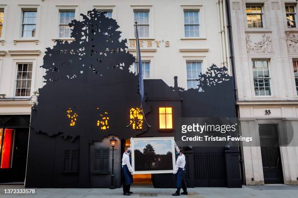 Sotheby’s technicians hold René Magritte’s masterwork, L’empire des lumières, outside the auction house’s New Bond Street entrance at Sotheby's on...