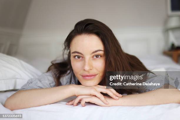 beauty portrait of a young brunette woman laying on a bed - allongé sur le devant photos et images de collection