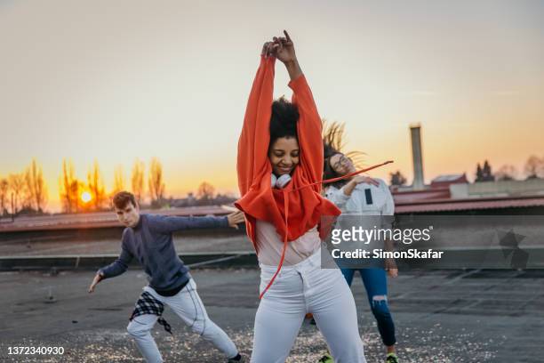 young man and women dancing break dance on roof at sunset - red headphones stock pictures, royalty-free photos & images