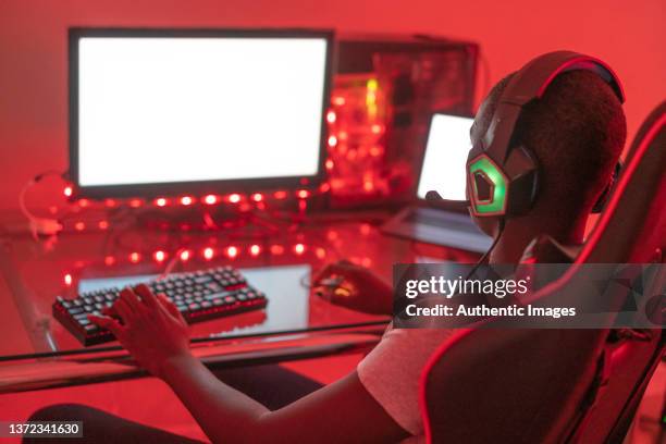 young black male gamer playing at station using desktop computer and laptop - gaming station stock pictures, royalty-free photos & images