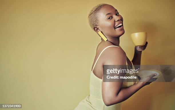 femme avec une tasse jaune regardant en arrière et souriant sur un fond jaune - women drinking coffee photos et images de collection