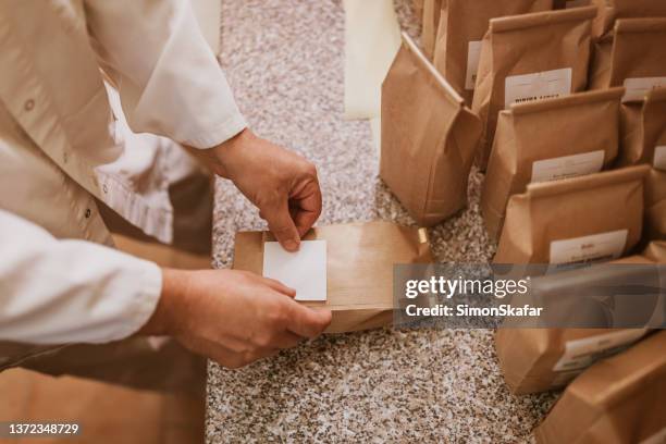 man applying label on paper bags in mill - etiketteren stockfoto's en -beelden