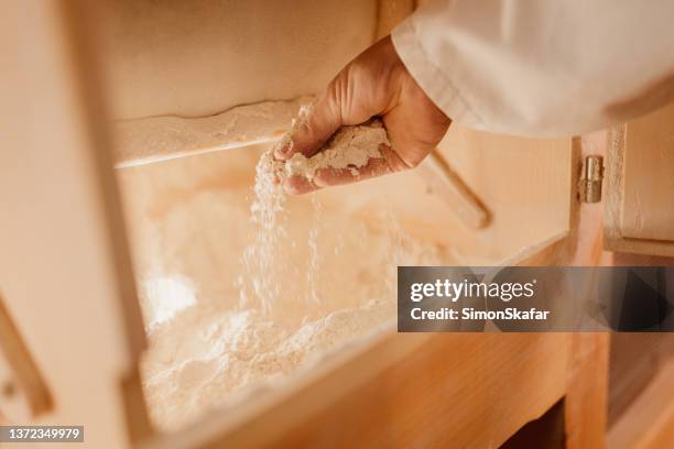 木製粉砕機内の小麦粉をチェックする男 - 挽く ストックフォトと画像