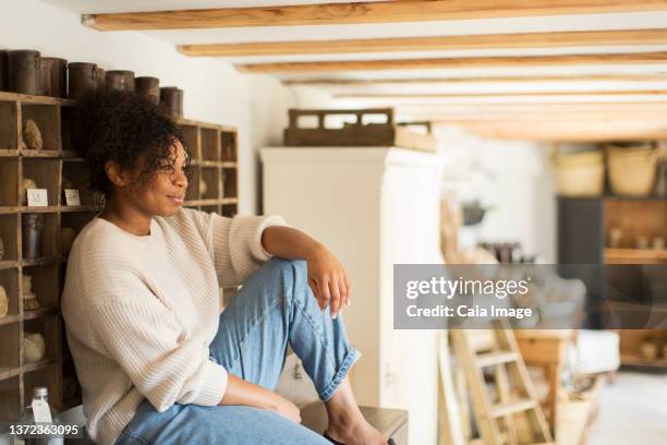 thoughtful female shop owner looking away - shabby chic imagens e fotografias de stock