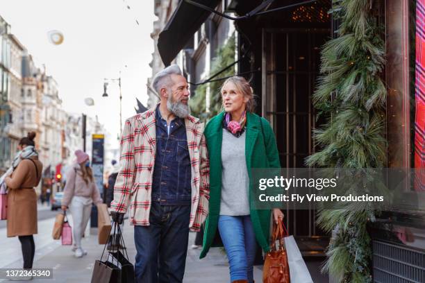 stylish senior couple christmas shopping in city - christmas cool attitude stock pictures, royalty-free photos & images