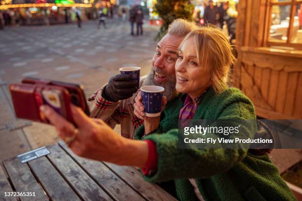 seniorenpaar macht selfies beim winter-reisekarneval - boomer couple out on town stock-fotos und bilder