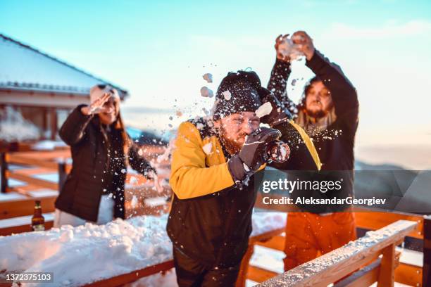 male trying to drink beer while getting snowballs thrown at him by friends - funny snow skiing stock pictures, royalty-free photos & images