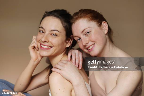 portrait of beautiful female friends standing together - sfondo beige foto e immagini stock