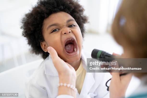 dentist examining a boy's teeth - gencive photos et images de collection