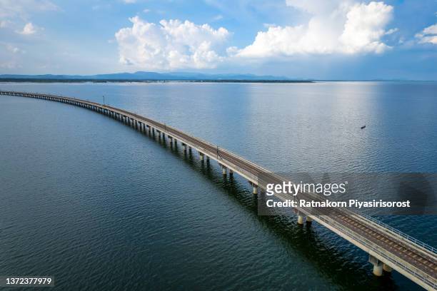 aerial view of thai local train on railway bridge at pa sak jolasid dam, the biggest reservoir in central thailand, in lopburi province with sea shore in transportation and travel concept. - biggest dam stock pictures, royalty-free photos & images