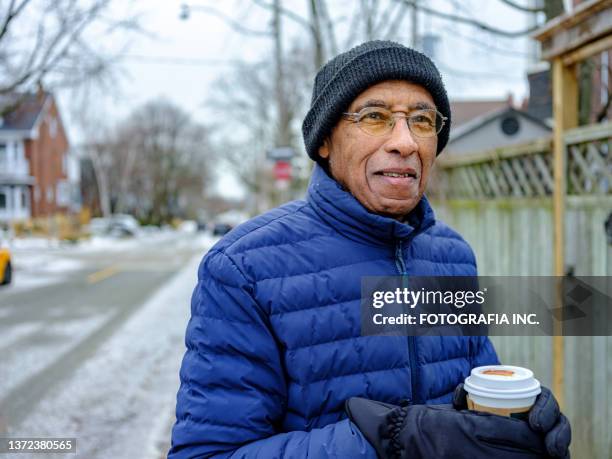 senior black man out for a winter walk and coffee - senior men coffee stock pictures, royalty-free photos & images