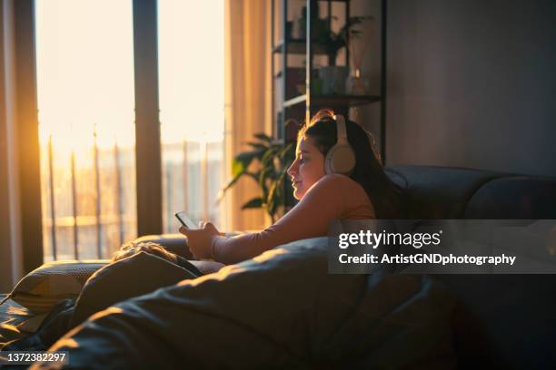 woman using technology on a beautiful morning. - bed sun stock pictures, royalty-free photos & images