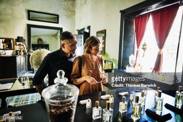 Medium shot of couple sampling perfume in boutique while shopping during vacation