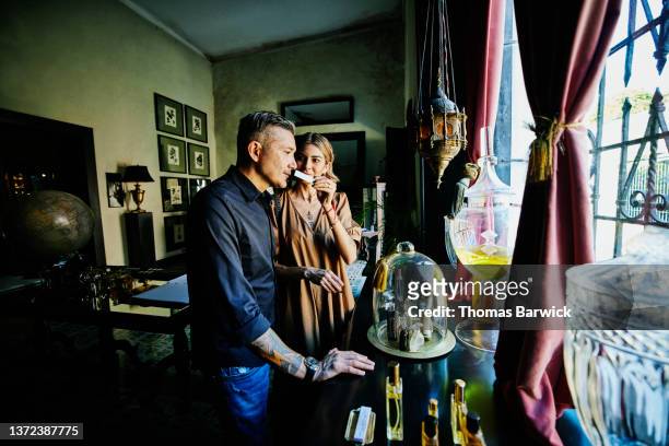 medium shot of couple smelling perfumes while shopping in perfumery during vacation - perfume stock pictures, royalty-free photos & images