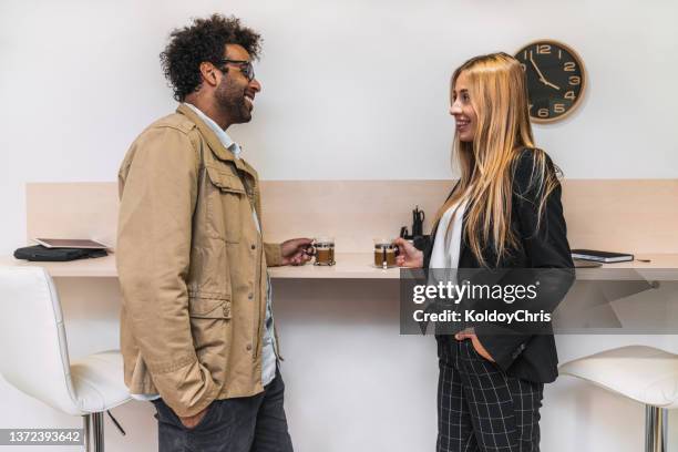 two colleague business people resting and chatting casually while drinking coffee - sharing coffee stockfoto's en -beelden