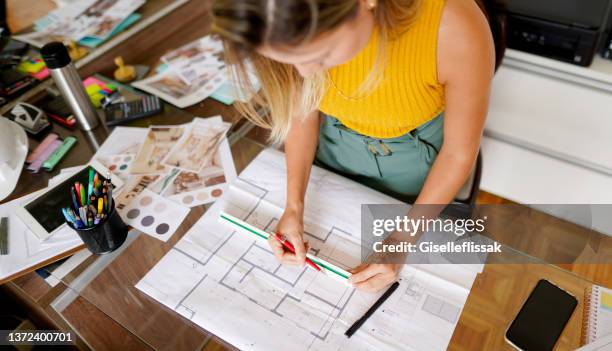 female architect measuring blueprints at a table in her office - ruler desk stock pictures, royalty-free photos & images