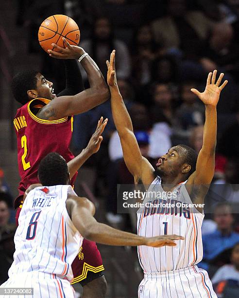 Cleveland Cavaliers Kyrie Irving releases a jump shot over Charlotte Bobcats Kemba Walker as teammate DJ White tries to assist on the play during...