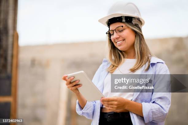architektin mit digitalem tablet auf der baustelle - bauingenieur stock-fotos und bilder
