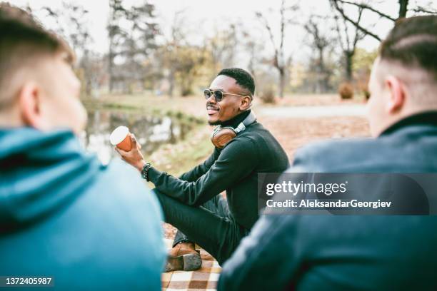 happy multi ethnic friends enjoying good cup of takeaway coffee in park - the soundtrack of my life stock pictures, royalty-free photos & images