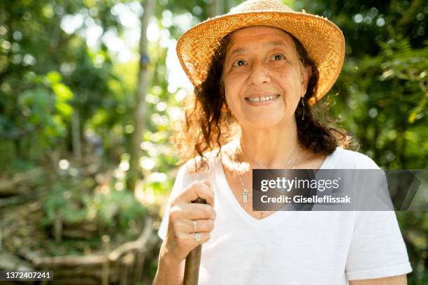 smiling senior woman doing some gardening in her lush yard - sun hat stock pictures, royalty-free photos & images