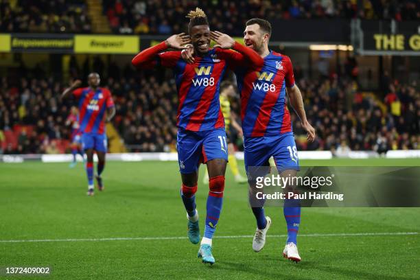 Wilfried Zaha celebrates with teammate James McArthur of Crystal Palace after scoring their team's third goal during the Premier League match between...