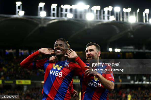 Wilfried Zaha celebrates with teammate James McArthur of Crystal Palace after scoring their team's third goal during the Premier League match between...