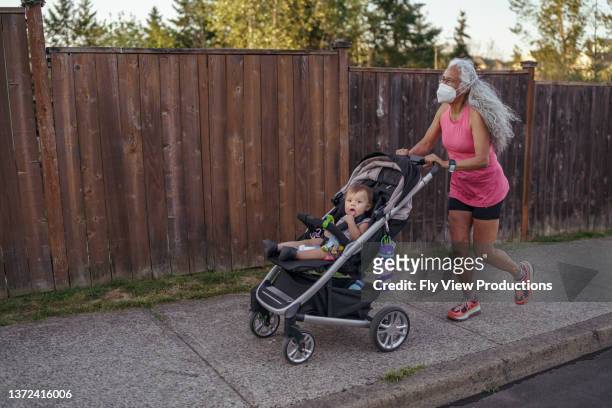 active grandmother jogging with stroller - athleticism stockfoto's en -beelden