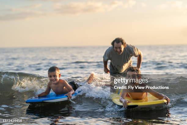 papa bringt söhnen das bodyboard bei - hawaii fun stock-fotos und bilder