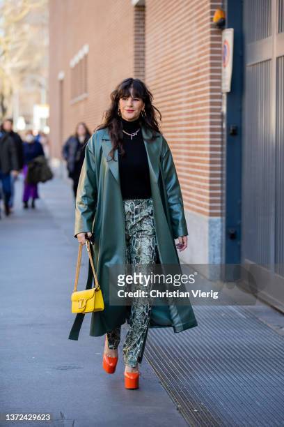 Gili Biegun seen wearing yellow Valentino bag, pants with slit & snake print, orange heels, green leather coat outside of Fendi fashion show during...