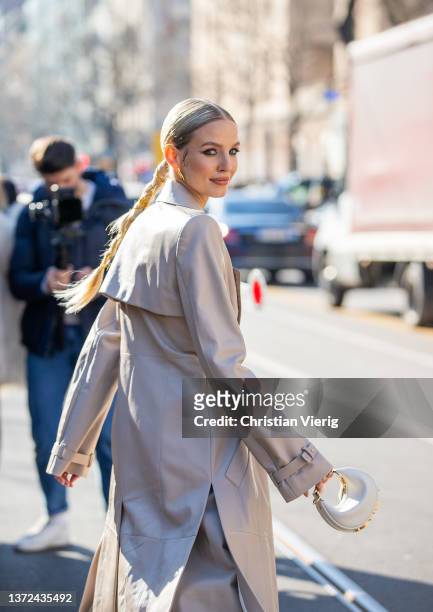 Leonie Hanne is seen with pigtail wearing earrings, grey belted trench coat, wide leg pants, mini bag Fendi outside of Fendi fashion show during the...