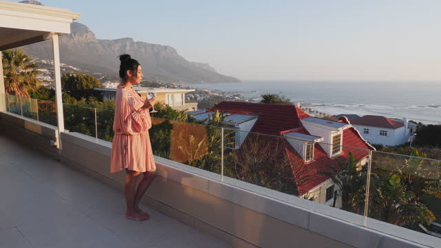 Woman drinking white wine on luxury patio with scenic ocean view