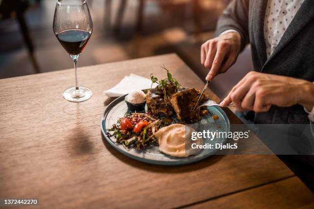unrecognizable young man eating lunch at a restaurant. - plate in hand stockfoto's en -beelden