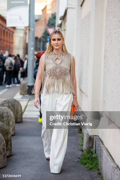 Valentina Ferragni seen wearing beige top with fringes, white wide leg pants, orange bag outside of Alberta Ferretti fashion show during the Milan...