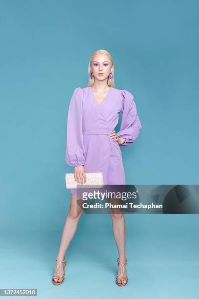 stylish woman in purple dress - sac à main blanc photos et images de collection